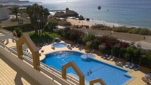 A hotel pool with two sections, a beach view, and a rocky coastline. - Hotel Luar (Portimão)