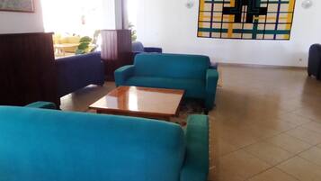 Une pièce avec des canapés de couleur turquoise, une table basse en bois et un motif décoratif sur le mur.