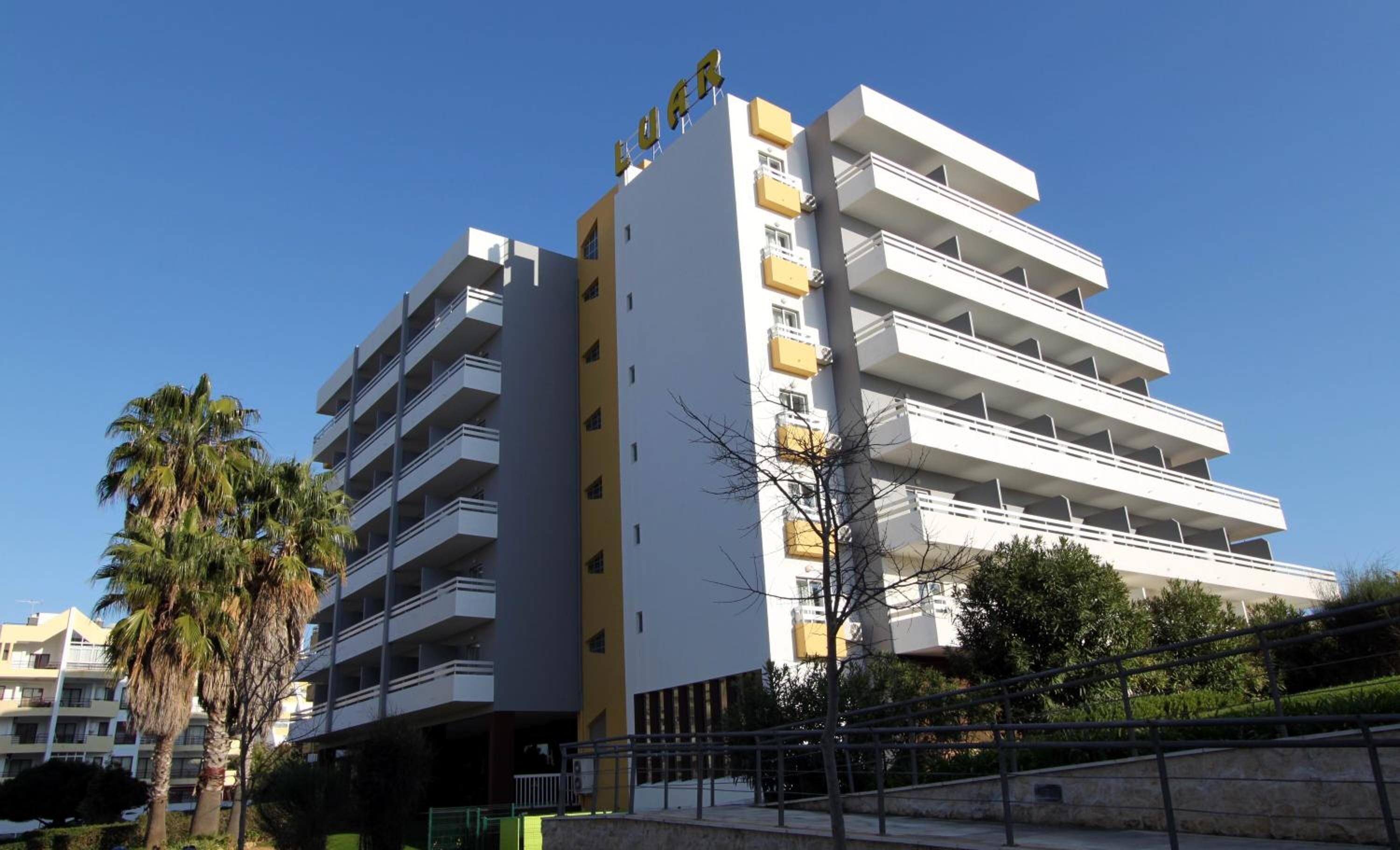 Un hotel de varios pisos con balcones y cielo despejado.