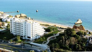 A coastal hotel with multiple white buildings, a beachfront, and rocky outcrops. - Hotel Luar (Portimão)