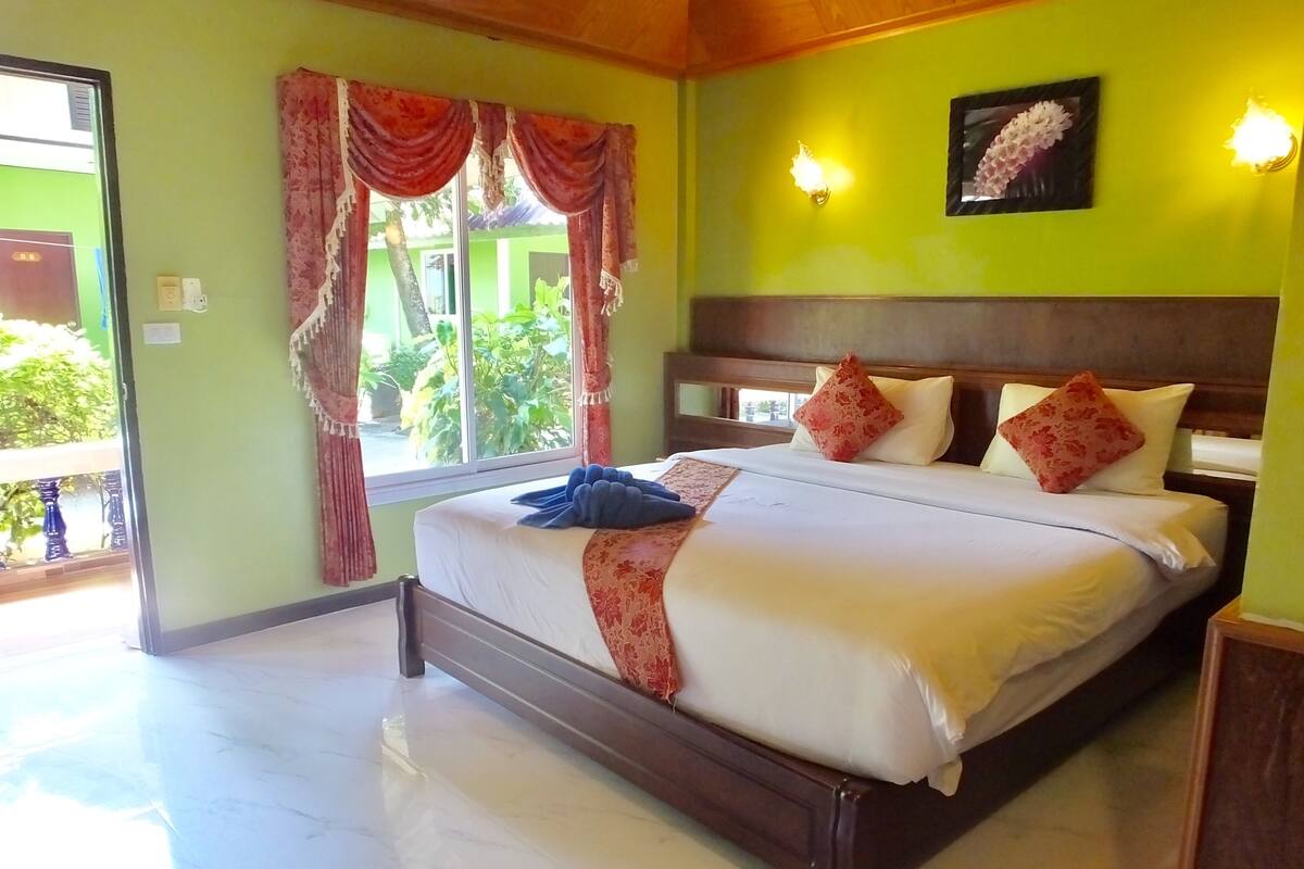 Habitación de hotel con cama, cortinas, una ventana y una lámpara fijada a la pared.