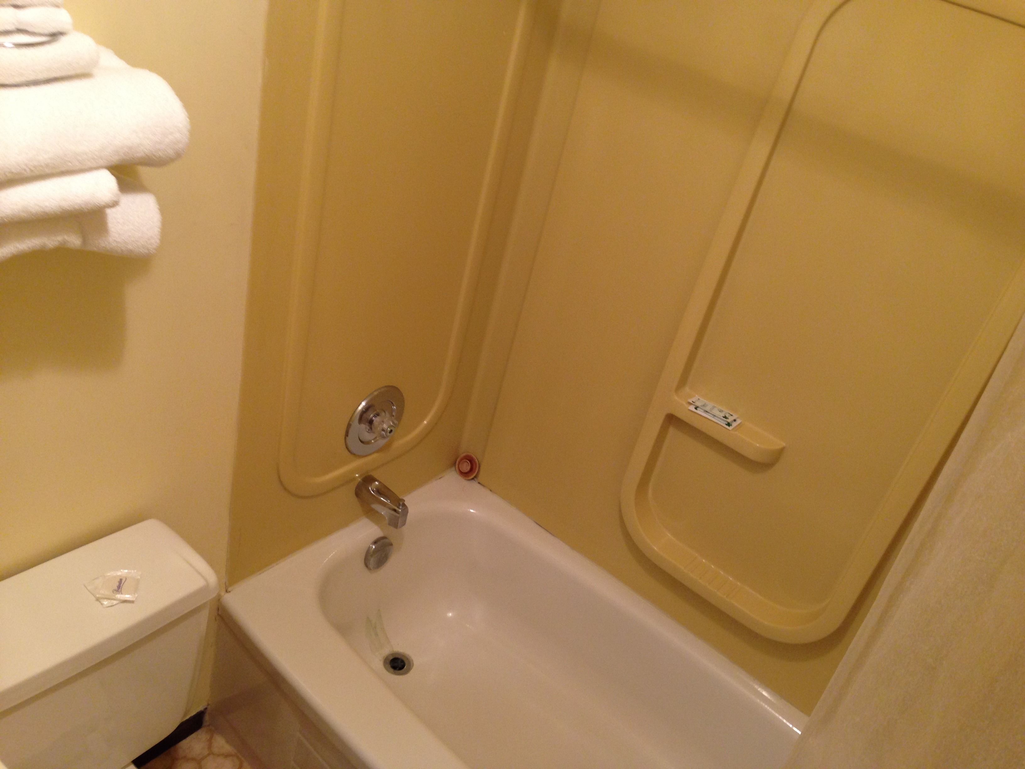 Un baño con una bañera blanca, un inodoro y un perchero con toallas dobladas.