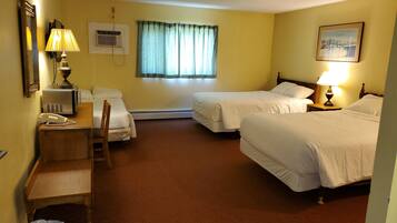 A hotel room with two beds, a desk with a lamp, a telephone, and a window with curtains.