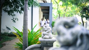 A stone lion statue in a garden with a pathway and greenery. - Hotel Alakamanda (Anuradhapura)