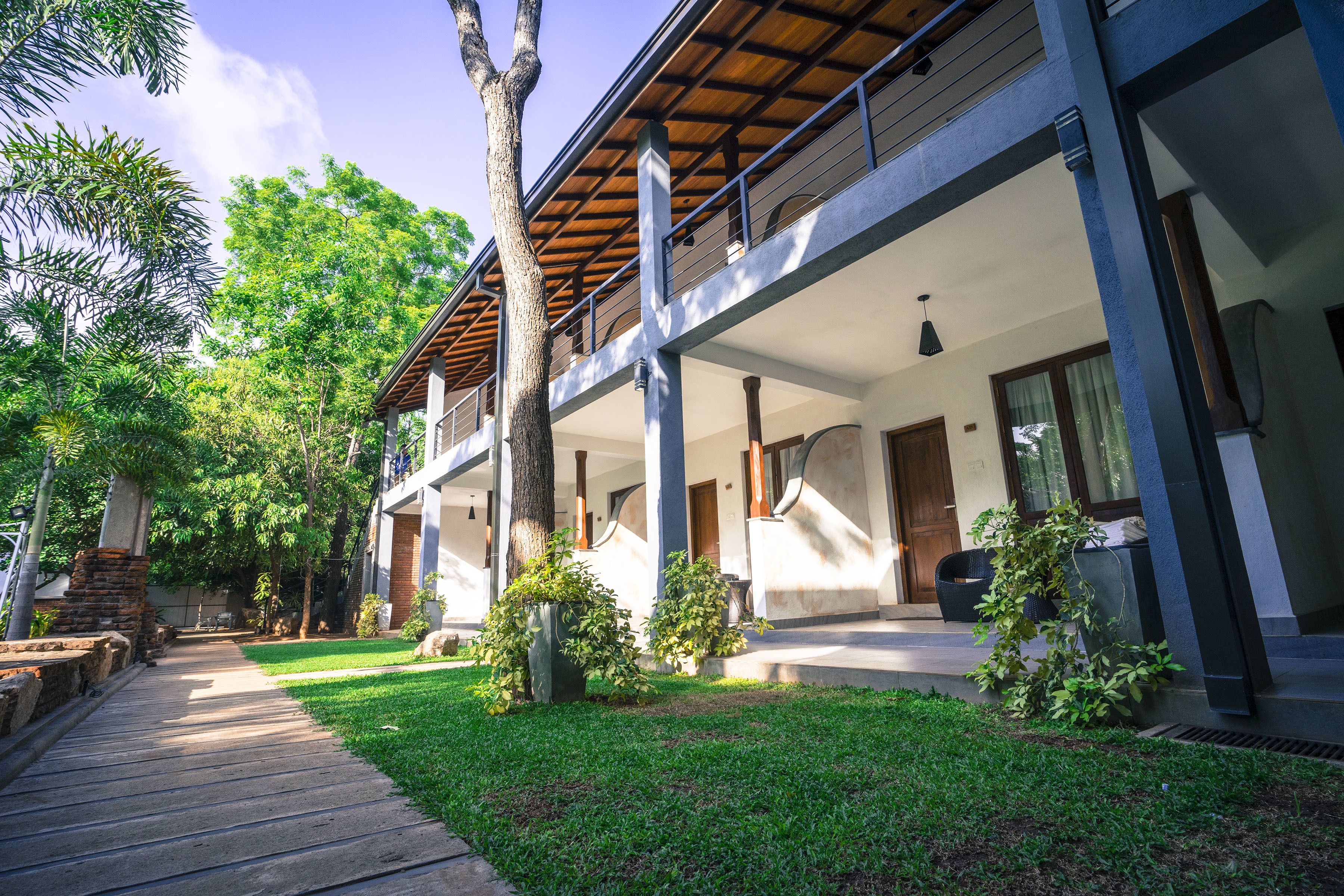 A modern building with a covered outdoor area, a wooden deck, and lush greenery.