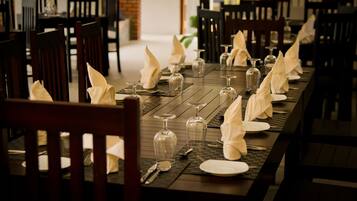 Una mesa de restaurante dispuesta con copas de vino, platos y servilletas.