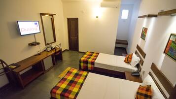 A hotel room with two single beds, a desk with a computer, a TV, and a mirror.