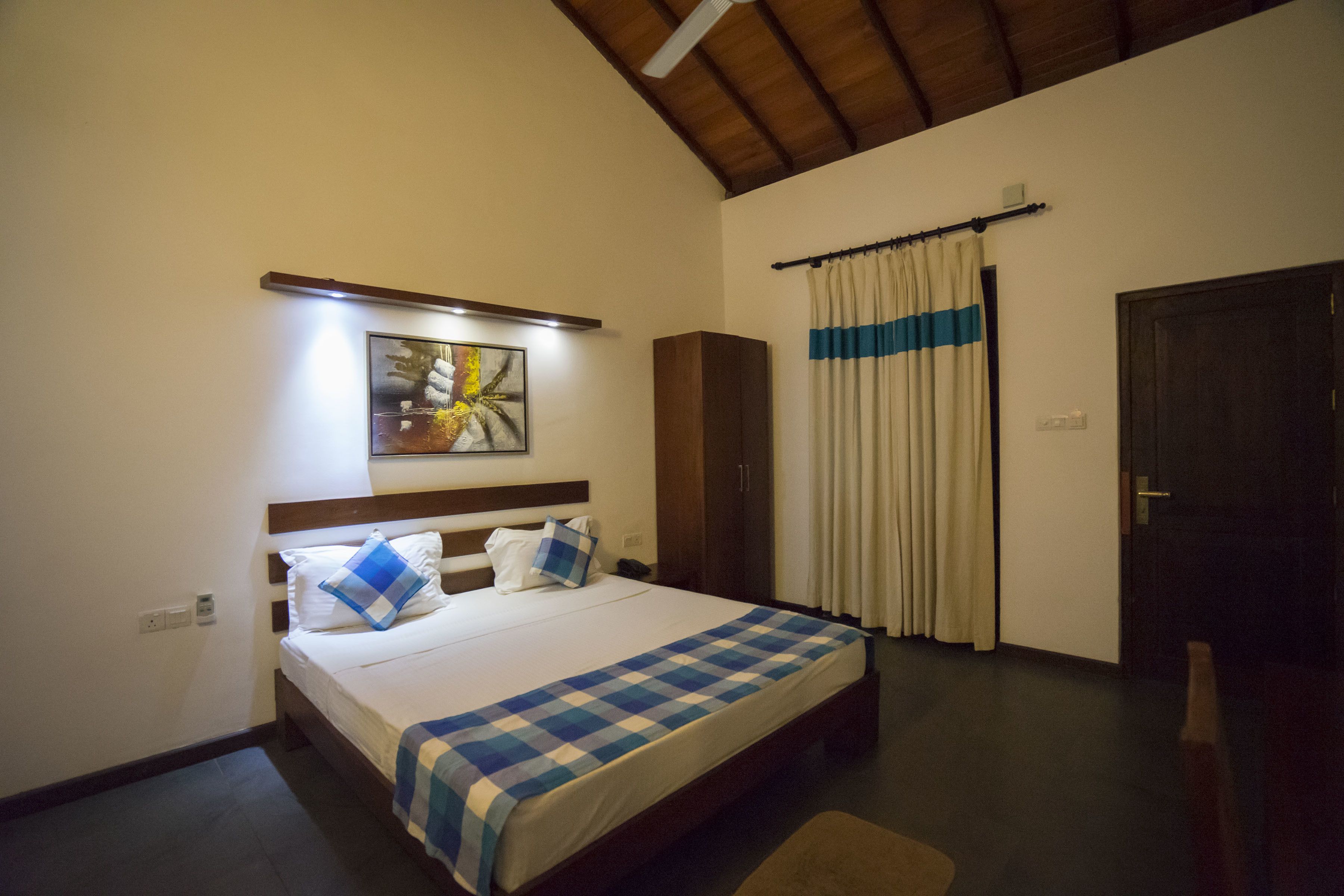 A bedroom with a bed, a nightstand, a wardrobe, a painting, and a curtain.