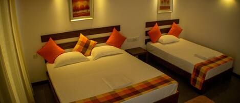 Two single beds with orange pillows, a checkered blanket, and a small orange rug.
