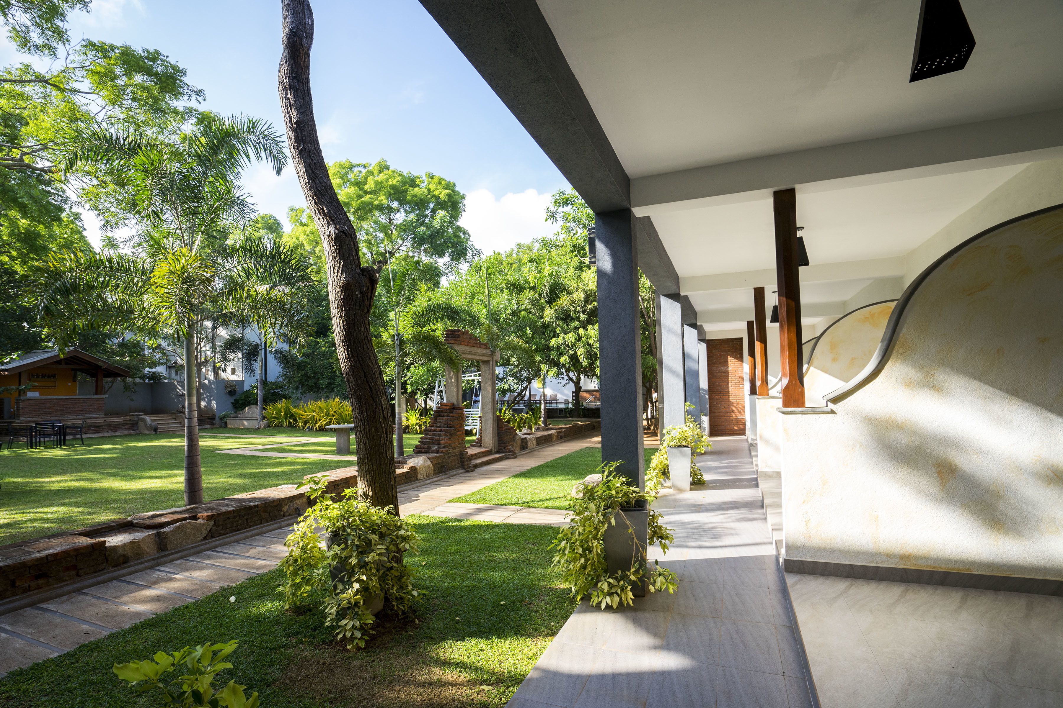 A covered outdoor area with a pathway, trees, and a building structure.