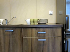 Eine Küche mit Holzschränken, einer Spüle aus Edelstahl und einem Kühlschrank.