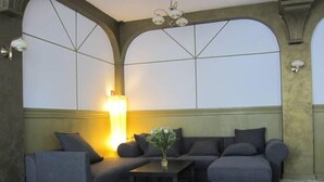 A room with a sectional sofa, a small table, and a floor lamp. - Hostel Wratislavia (Wroclaw)