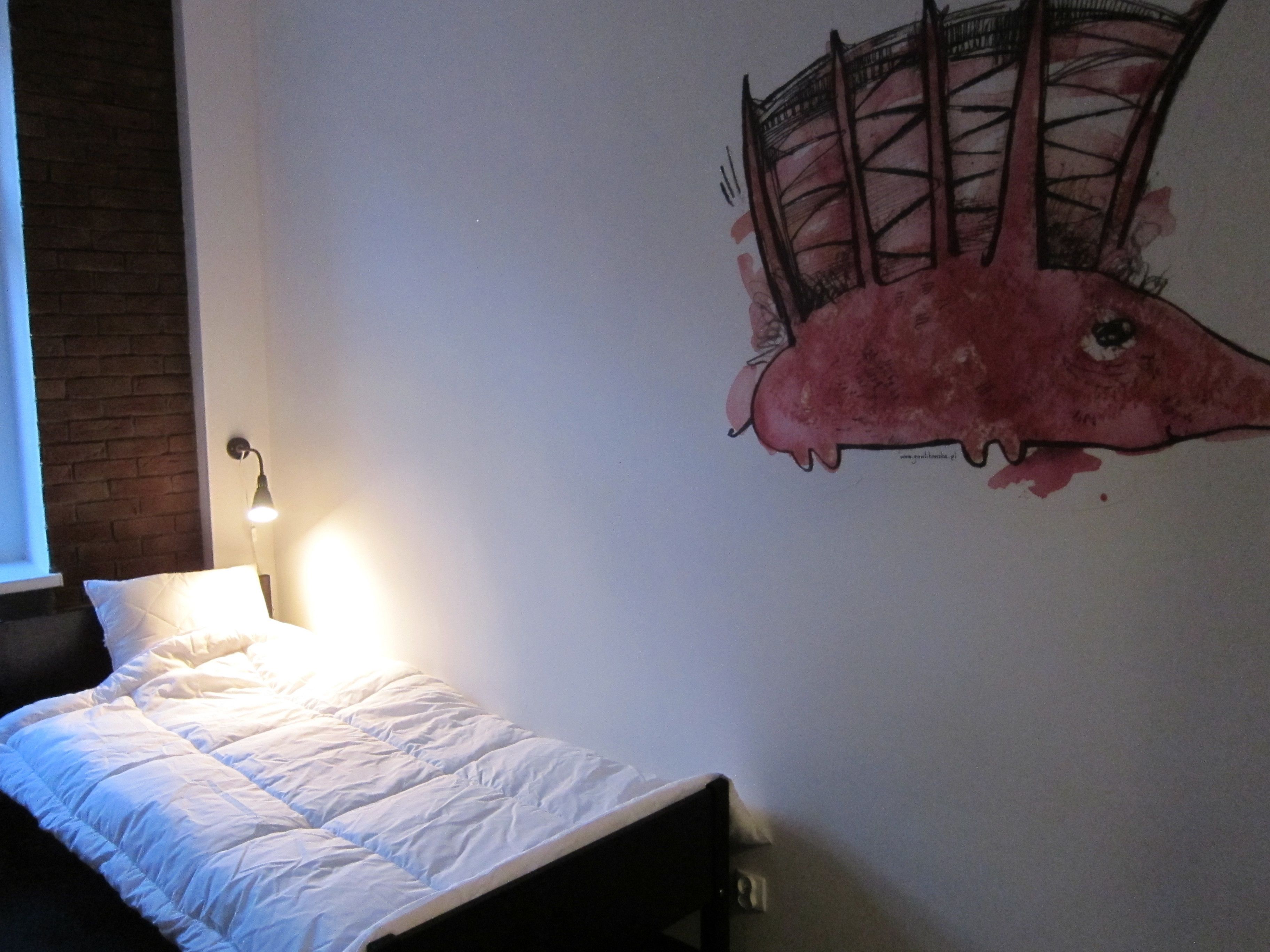 Un dormitorio con cama, una lámpara de pared y un mural grande.