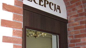 A reception area with a sign reading "RECEPCJA," a chandelier, and a wooden cabinet with drawers. - Hostel Wratislavia (Wroclaw)