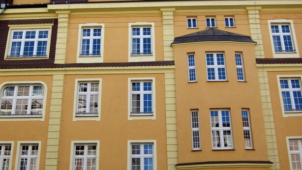 A multi-story building with yellow and brown facades, multiple windows, and a visible entrance with a stone archway. - Hostel Wratislavia (Wroclaw)