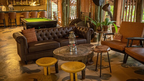 Een bar met een pooltafel, een leren bank en barkrukken.