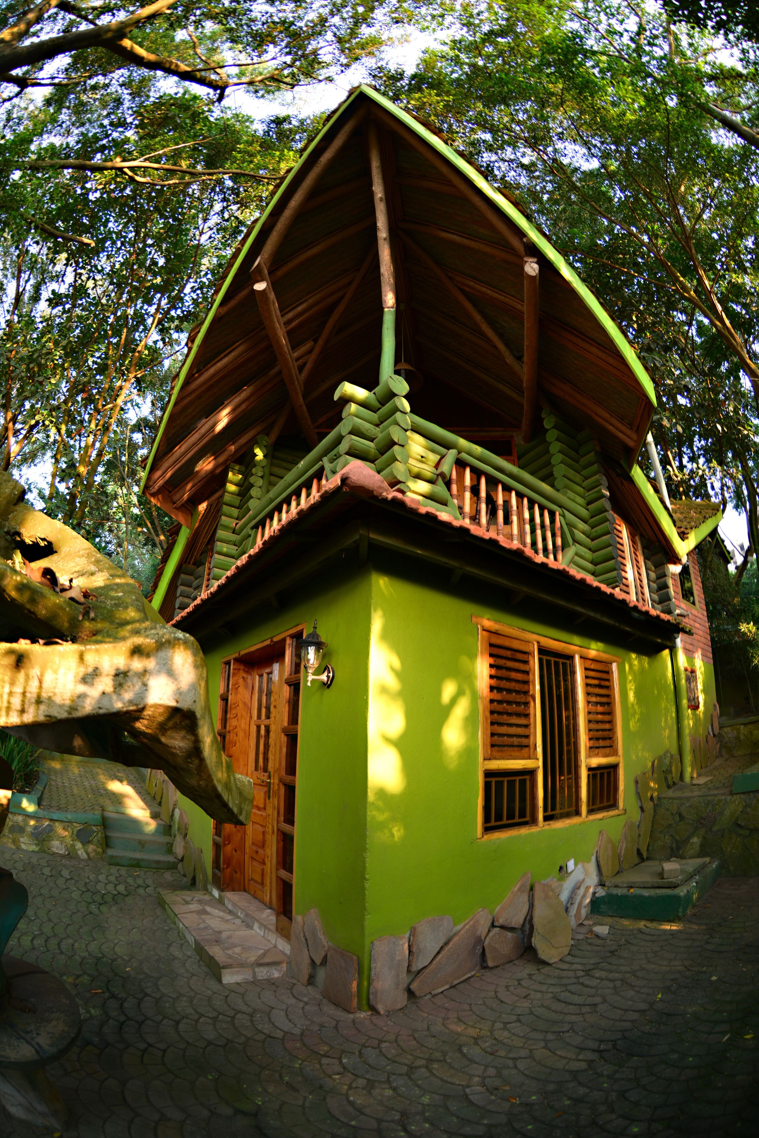 Una casa verde con un balcón de madera, escalones de piedra y una puerta de madera.