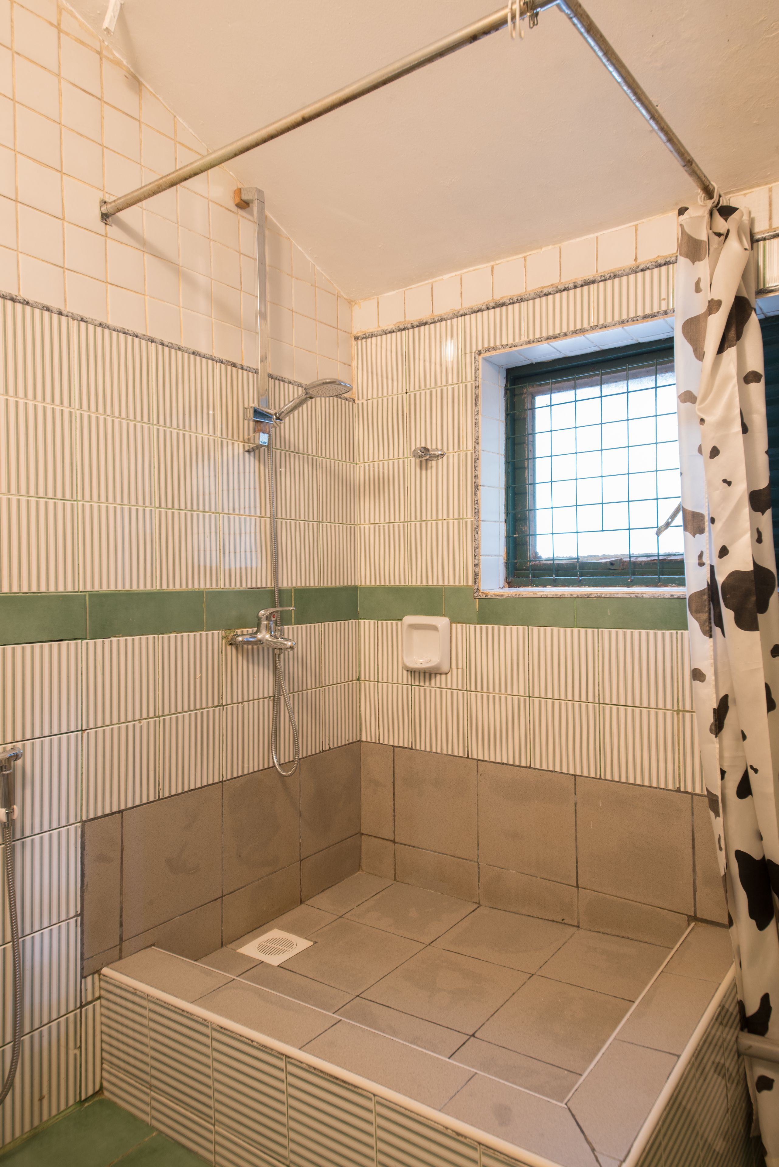Un espacio ducha con ventana, toallero y cabezal de ducha.