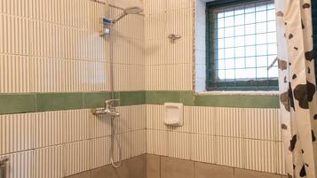 Un espacio ducha con ventana, toallero y cabezal de ducha.