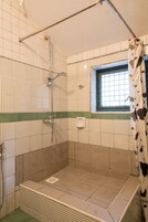 Un espacio ducha con ventana, toallero y cabezal de ducha.