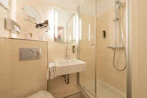 Un baño moderno con cabina de ducha de vidrio, un lavabo blanco y un espejo sobre él.