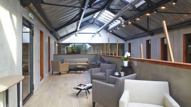 Un espacio interior amplio con techo alto, muebles modernos y vistas a través de grandes ventanales.