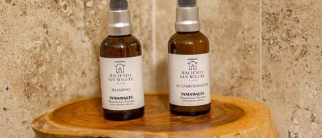 Two bottles of shampoo on a wooden surface against a textured wall.