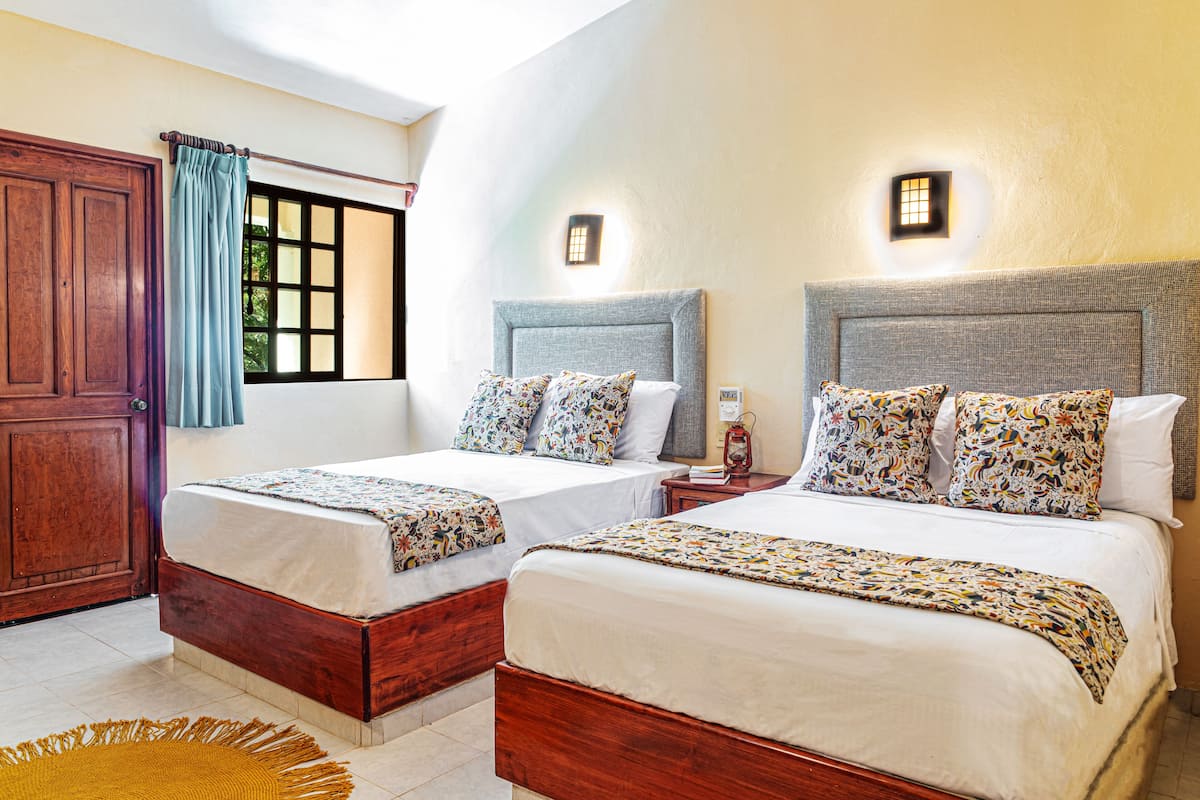 A hotel room with two beds, wooden headboards, and a large window with curtains.