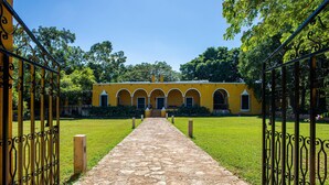 Un sentiero conduce a un edificio giallo con finestre ad arco e un ingresso in pietra.