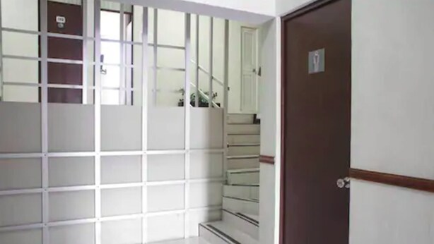 A hallway with a staircase leading to a door marked with a wheelchair accessibility sign. - Hotel Fiesta Versalles (Monterrey)