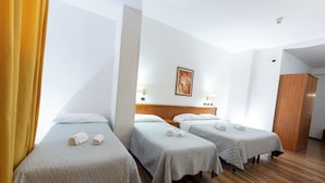 Une chambre d’hôtel avec deux lits simples, un plancher en bois, une armoire en bois et un tableau au mur.