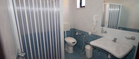 A bathroom with a shower, toilet, sink, and mirror.