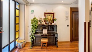 Un piano, un banc, une plante et une porte avec une pancarte indiquant les numéros des pièces, de 1 à 9.