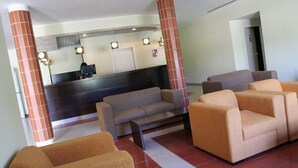 Un hall con mostrador de recepción, sofás y una mesa de centro.