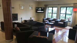 Amplia sala de estar con varios sofás y un televisor de pantalla plana montado en la pared.