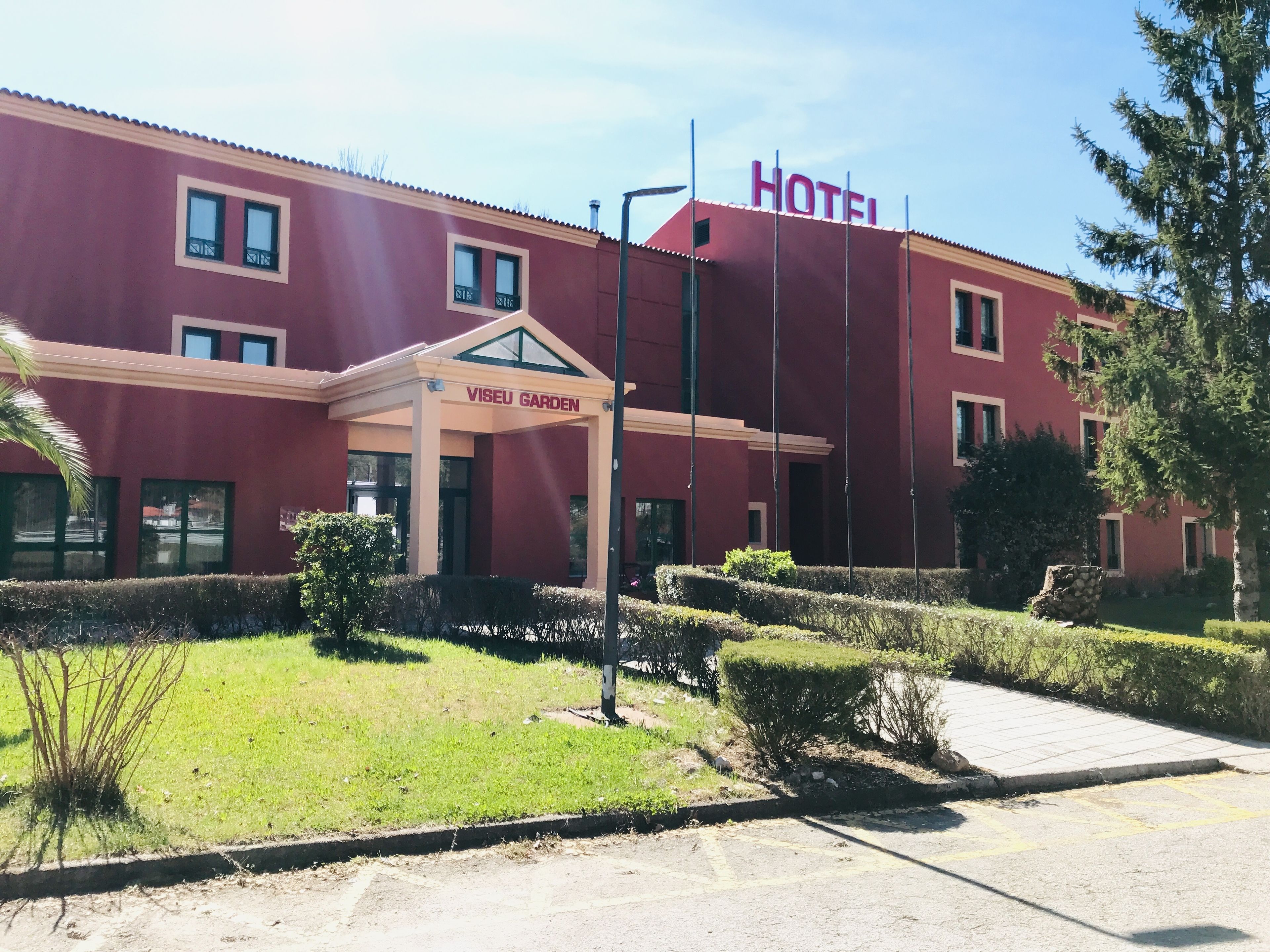 Un hotel con fachada roja, un letrero que dice "VIEU GARDEN" y un cielo despejado.