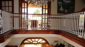 Un interior de varios niveles con una escalera de madera, un candelabro y vistas al exterior.