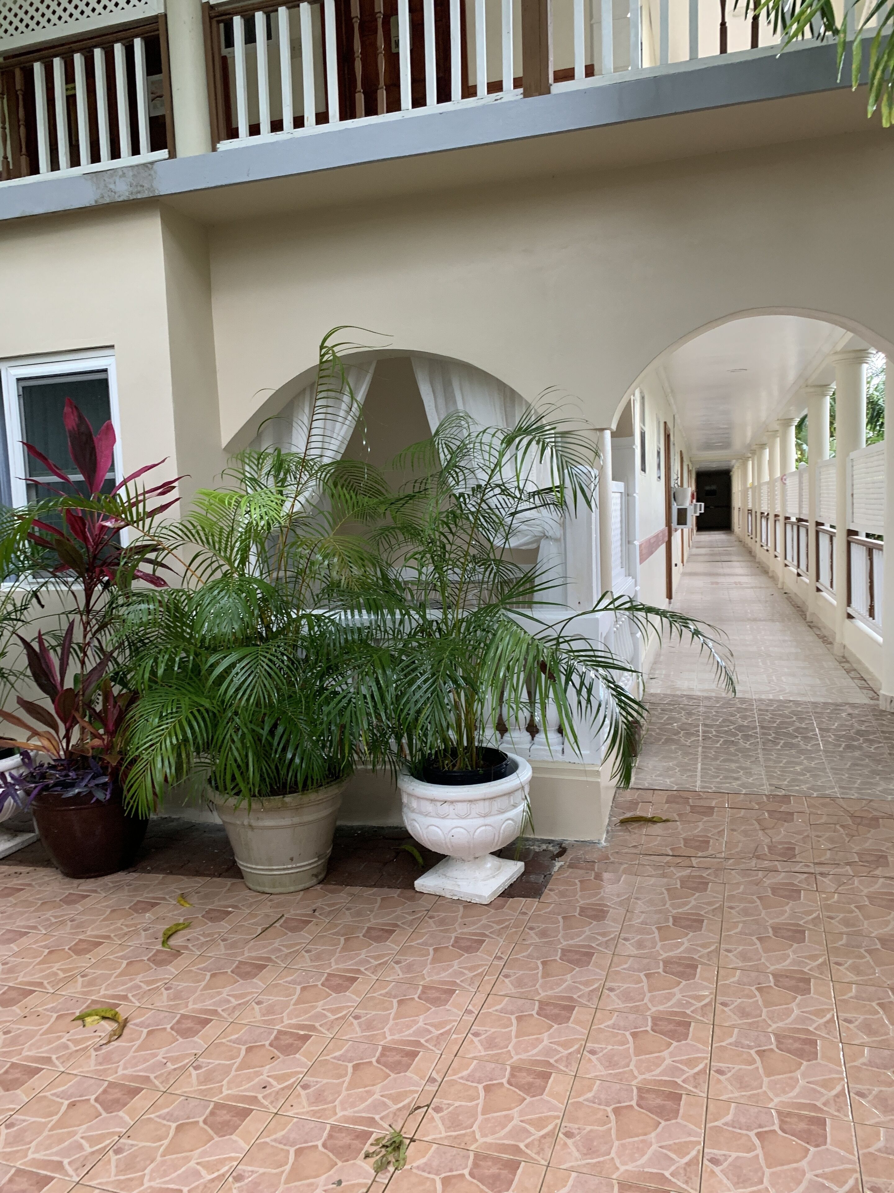 A covered walkway with potted plants and a tiled floor.