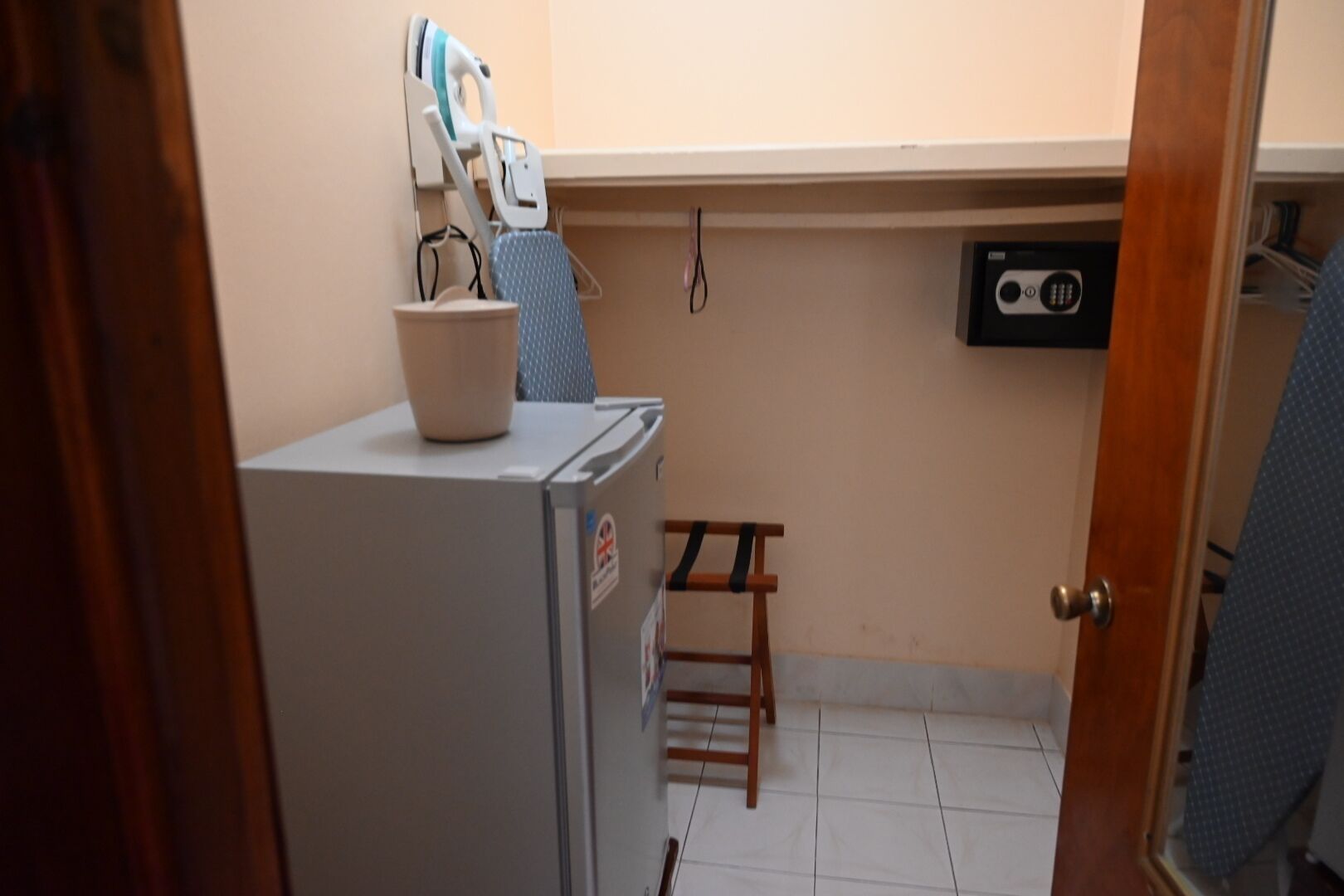 A compact kitchen with a refrigerator, a small table, and a wall-mounted ironing board.