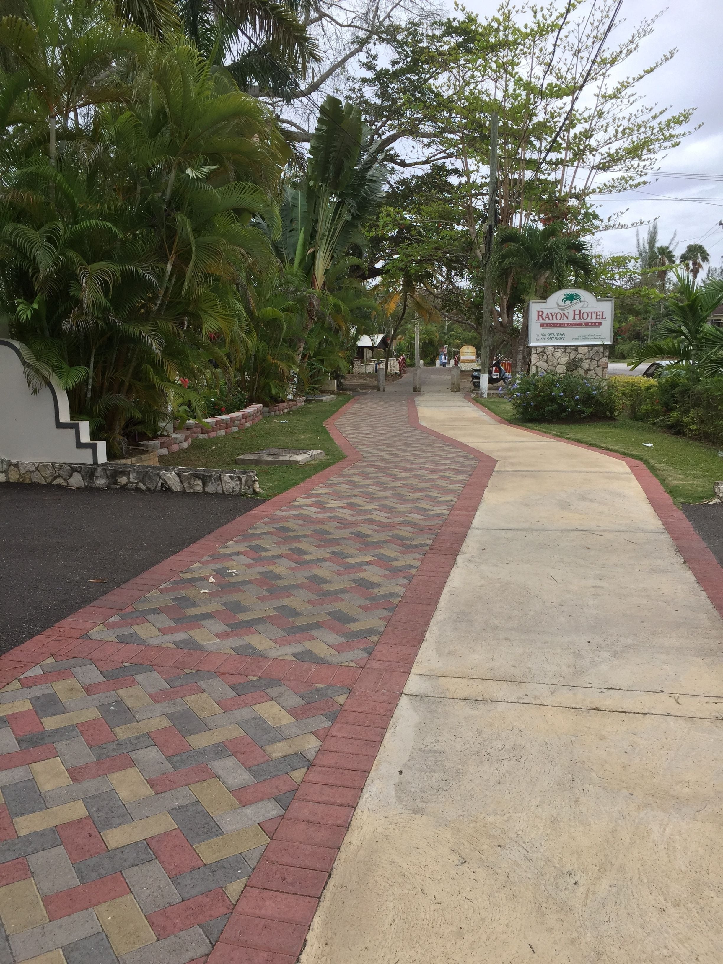 Un sendero que conduce a la entrada de un hotel, con un cartel que dice 'Rayon Hotel'.
