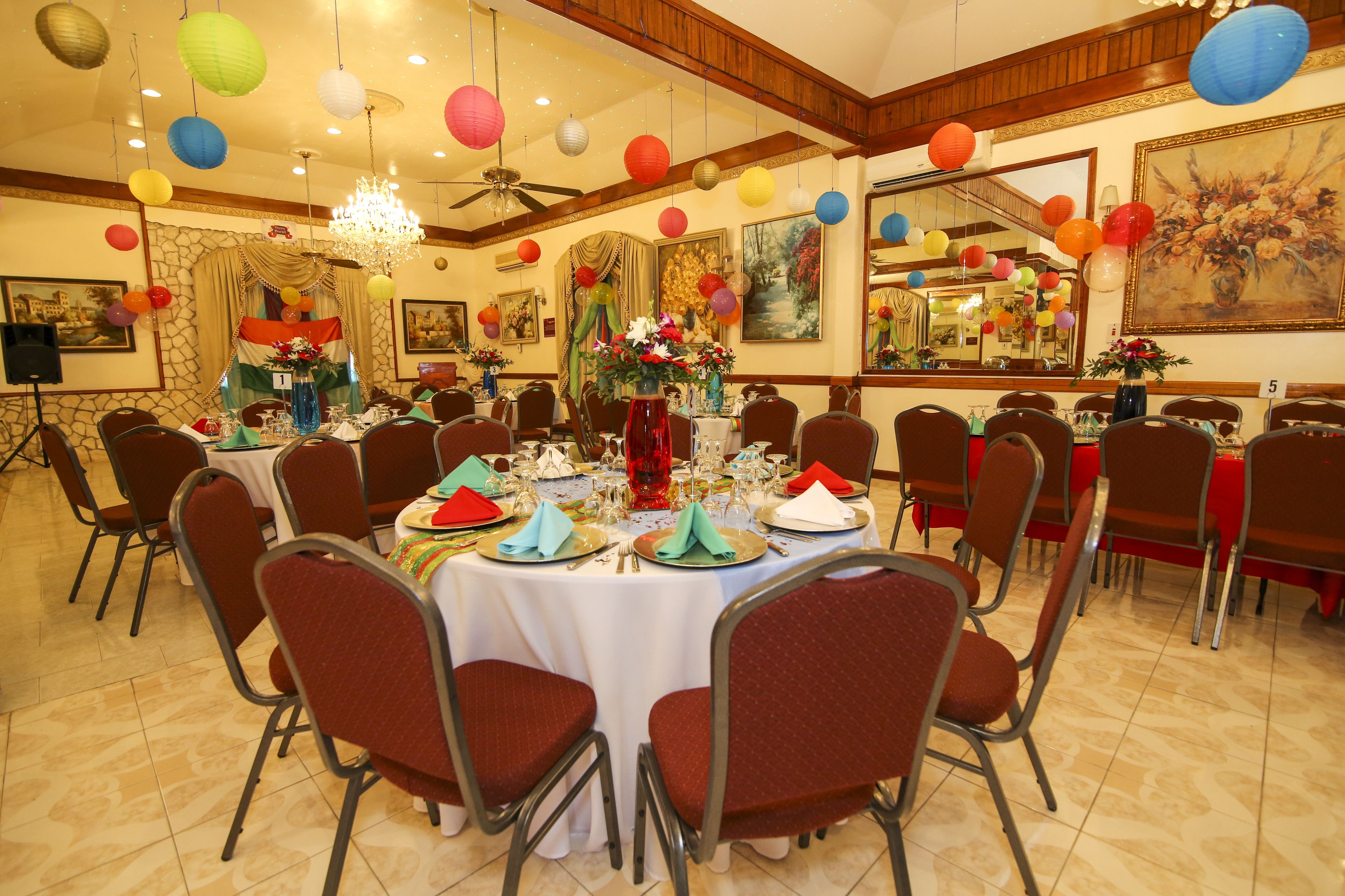 A banquet hall with round tables set for dining, chairs, and a chandelier.