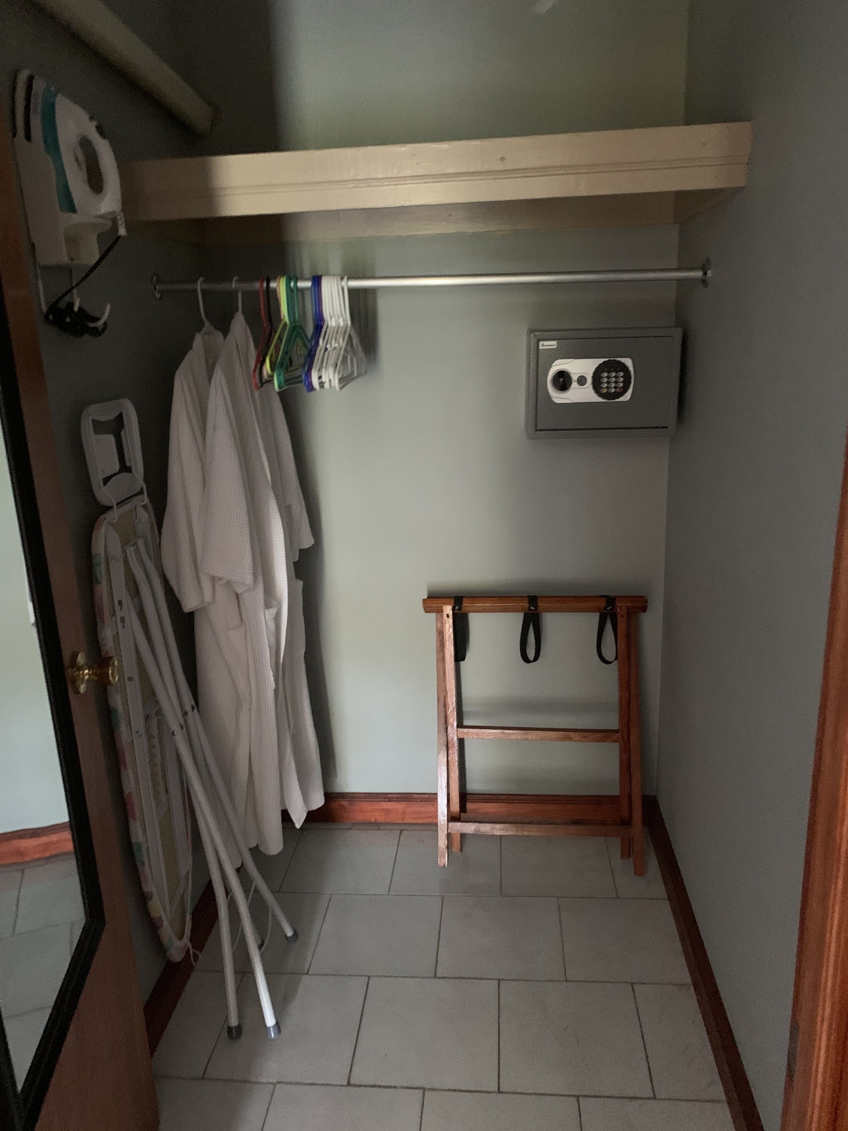 A small laundry room with a wooden shelf, a drying rack, and a wall-mounted dryer.