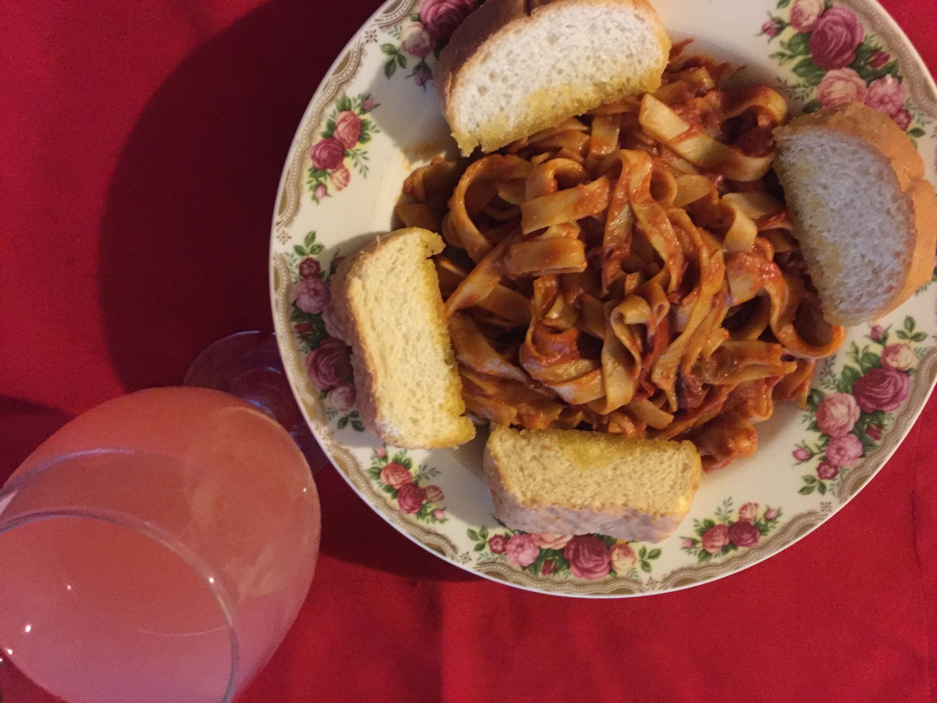 A plate of pasta with bread on a floral tablecloth.