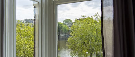 A room with a large window overlooking a river and a cityscape.