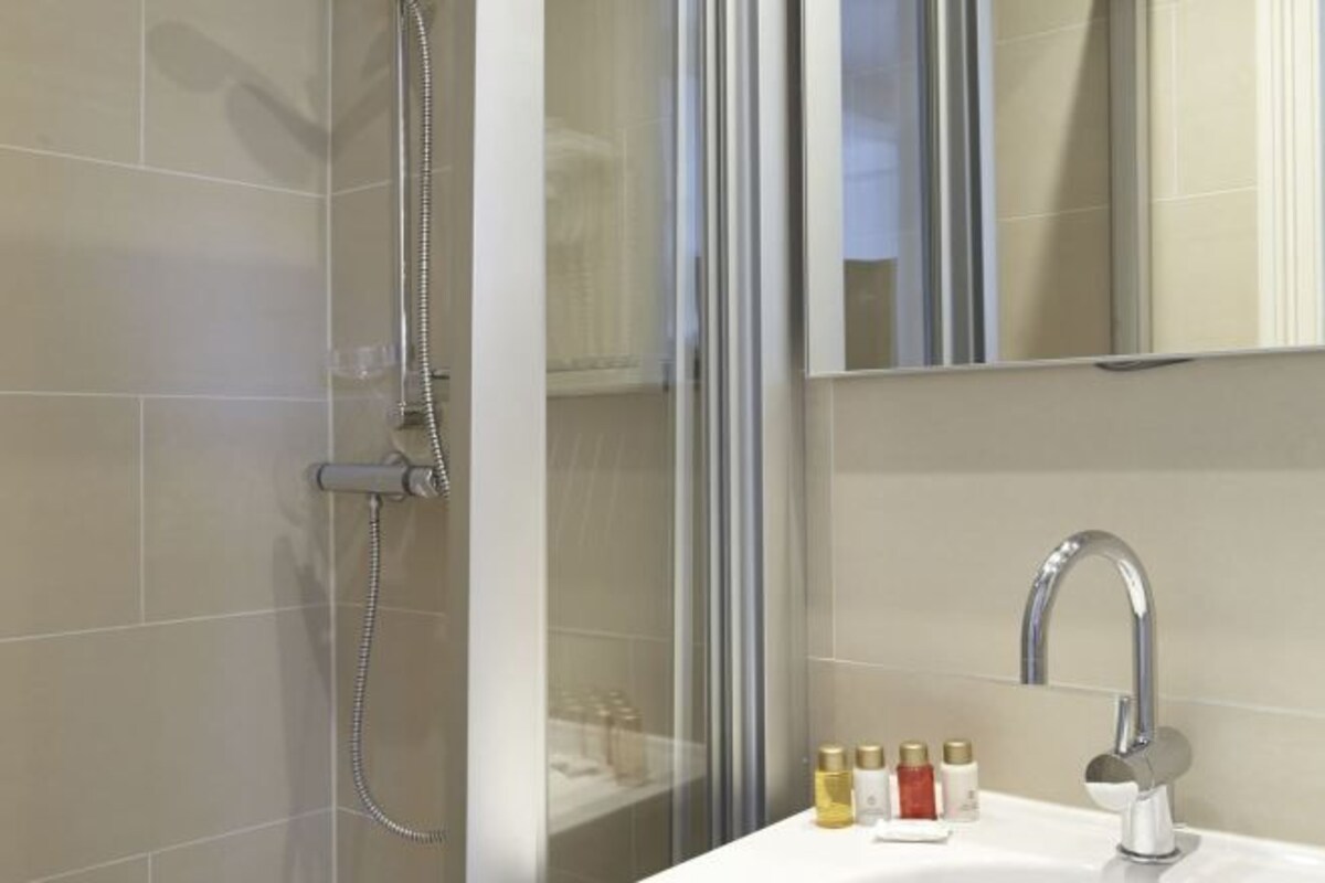 A modern bathroom with a shower, a sink, and a mirror.
