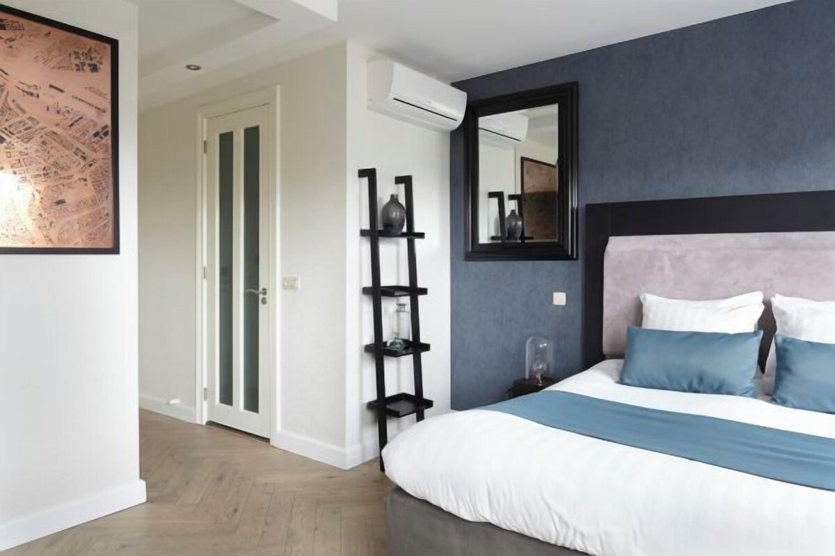 A bedroom with a bed, a mirror, a shelf, and a door.