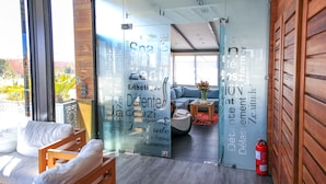 A modern hotel lobby with a glass partition, wooden furniture, and a fire extinguisher. - Medina Loft & Spa (Marrakech)