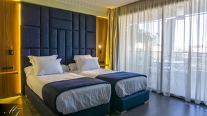 A hotel room with two beds, a large window with sheer curtains, and a wooden door. - Medina Loft & Spa (Marrakech)