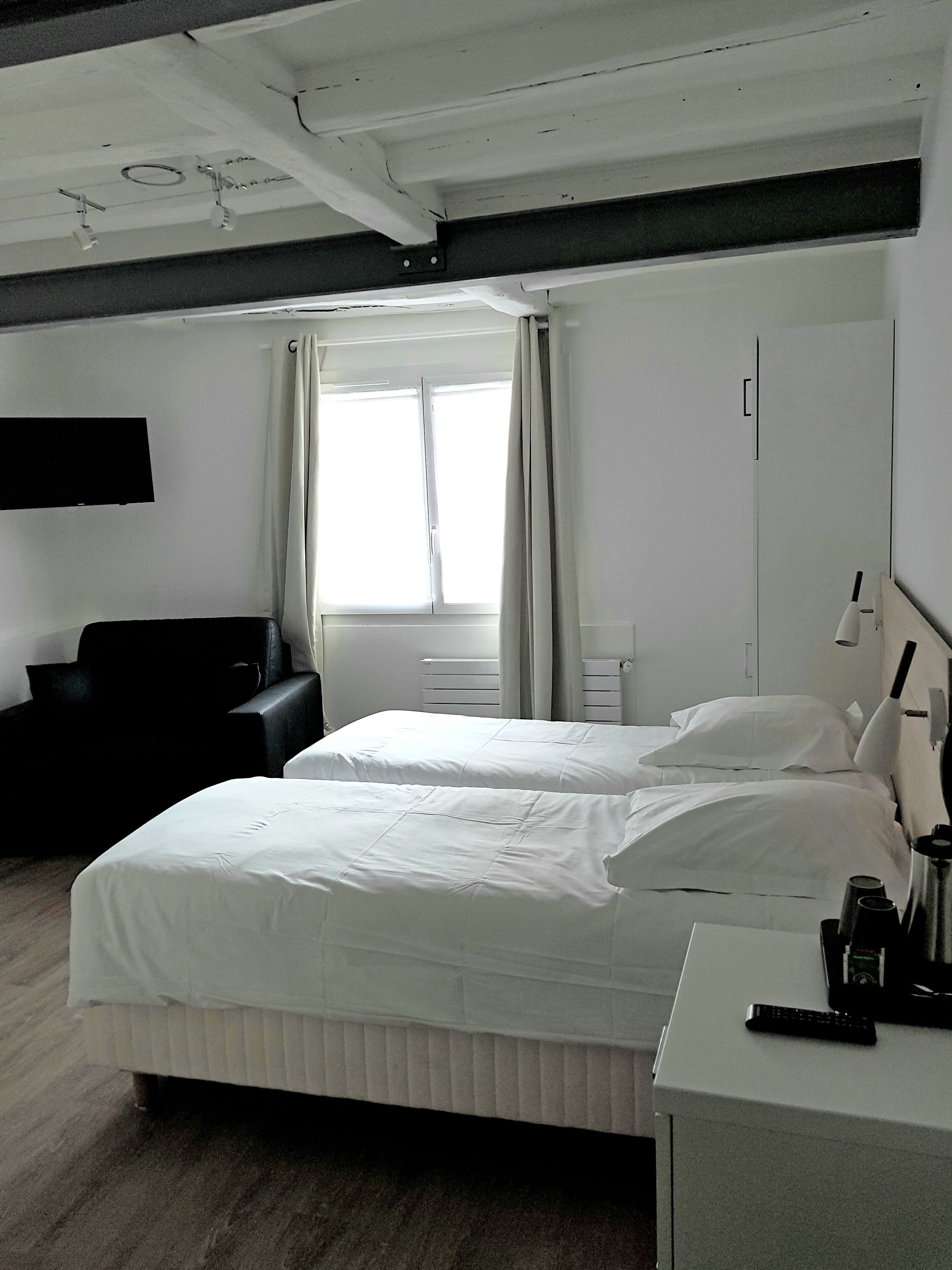 Una habitación de hotel con una cama grande, un escritorio con lámpara, una silla y un televisor fijado a la pared.