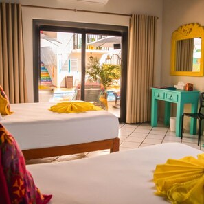 Habitación de hotel con cama, escritorio, silla, ventana con cortinas y vista a una piscina y zona exterior.